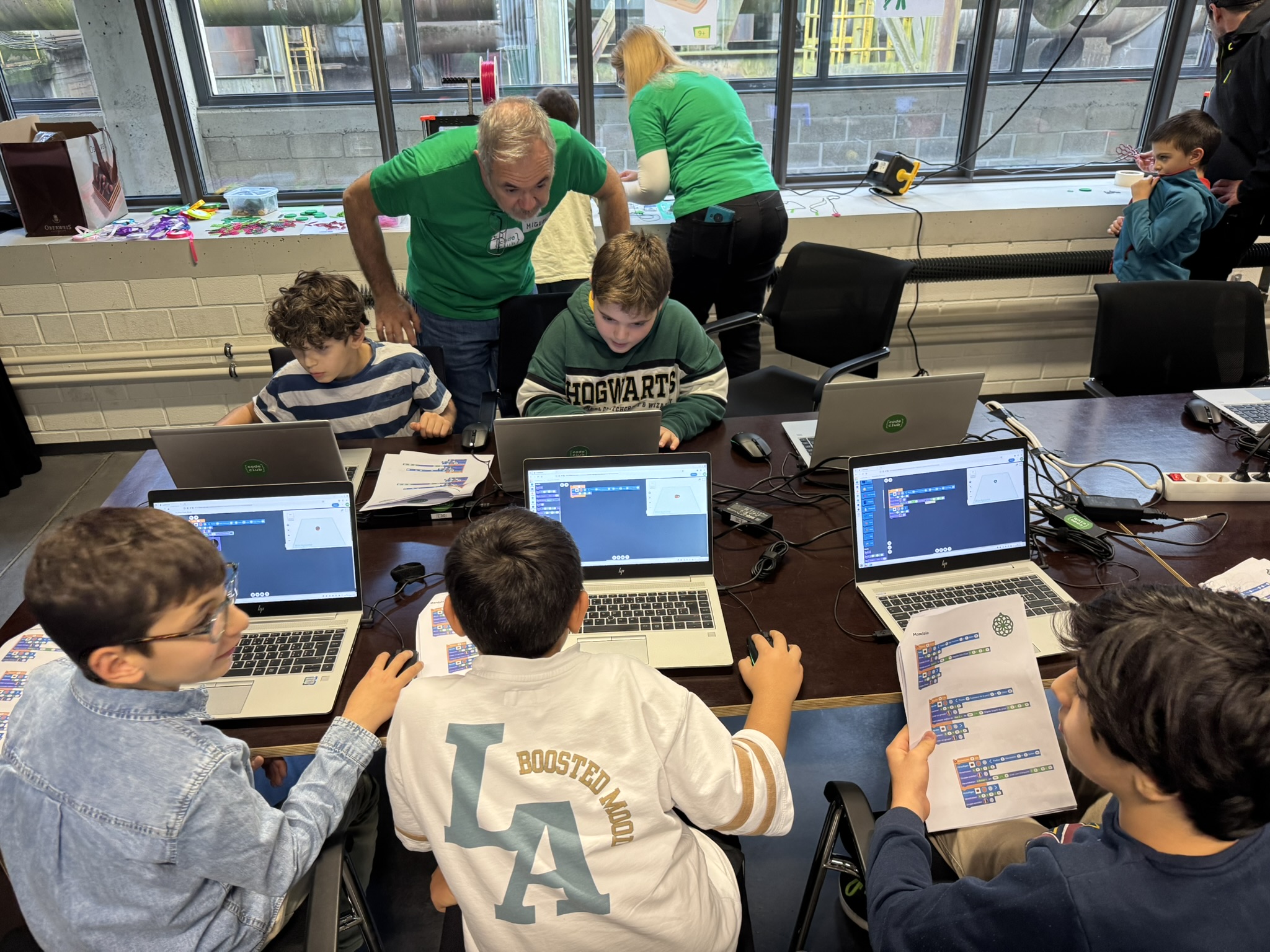 Konzentrierter junger Mensch vor dem Bildschirm während eines Coding-Treffens, begleitet von einem Coach